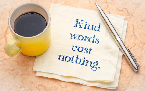 Image of coffee and pen with the quote, "Kindness Costs Nothing"